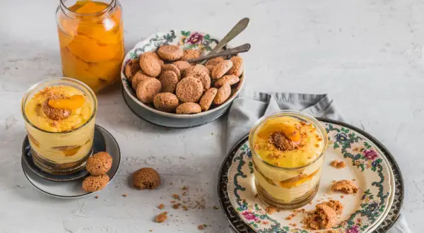 Delizioso tiramisù alle pesche in bicchiere, con amaretti e pesche sciroppate.