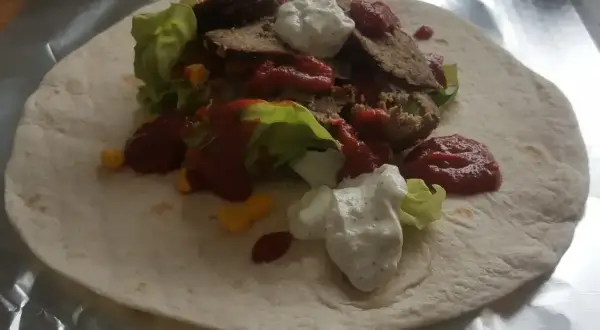Domowy kebab z baraniną, sałatą, kukurydzą, sosem pomidorowym i jogurtowym na tortilli.