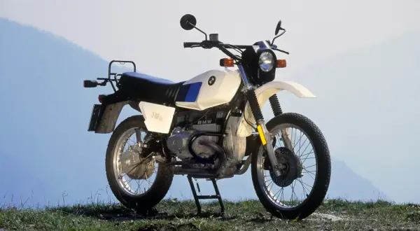 Una BMW R80GS, una icónica moto de los 80, lista para la aventura en un paisaje montañoso.
