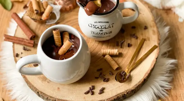 Cioccolata calda cremosa in tazza, con biscotti arrotolati e tavoletta di cioccolato. Un abbraccio goloso per le giornate autunnali.