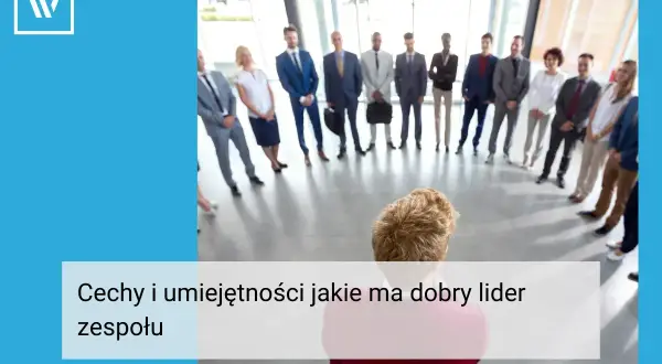 Grupa ludzi w garniturach stoi w kręgu, słuchając swojego **team leadera**.