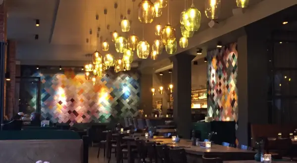 Mysig restaurang i Berlin med många vackra lampor och en färgglad vägg. Perfekt för en middag på en av Berlins bra restauranger.