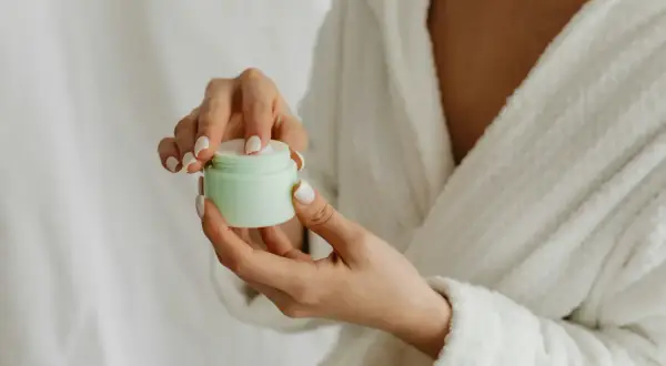 Hände mit gepflegten Nägeln öffnen eine Creme. Die positive resveratrol wirkung haut wird durch diese Pflege unterstützt.