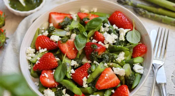 Frischer Spargelsalat mit Erdbeeren, Feta und Basilikum, beträufelt mit Pesto. Ein leichter Genuss für den Frühling.