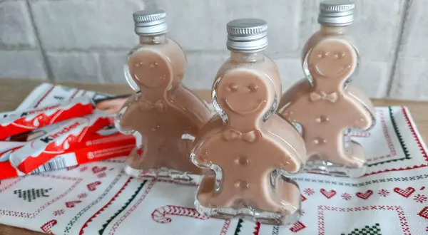 Trzy buteleczki likieru w kształcie ludzików z piernika, obok batoniki Kinder.