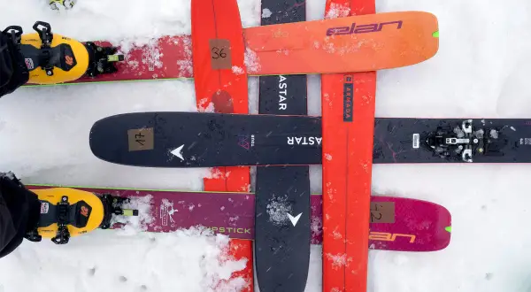 Skier mit gelben Tourenschuhen und Skiern in verschiedenen Farben, darunter ein schwarzer Ski mit der Aufschrift "black crows navis freebird".