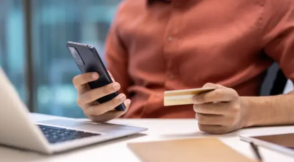 Mężczyzna trzyma telefon i kartę, szukając informacji, jak zrezygnować z Tidal.