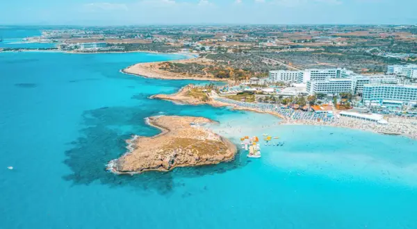 En livlig strand med turkost vatten, solbadande och vattensporter. Perfekt för Ayia Napa aktiviteter.
