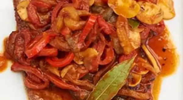 Ein saftiges Paprikaschnitzel-Rezept mit geschmortem Paprika, Zwiebeln und Pilzen, garniert mit einem Lorbeerblatt.