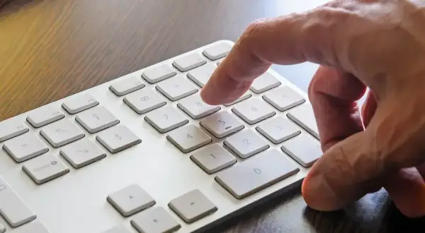 Dłoń naciska klawisz 8 na klawiaturze numerycznej, aktywując funkcję num lock.