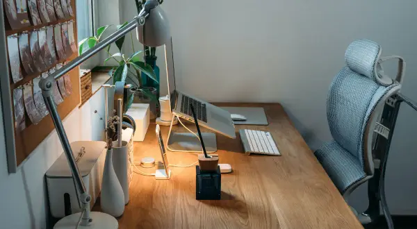 Bureau en bois avec plan de travail, ordinateur portable, lampe, clavier et chaise ergonomique. Une idée d'espace de travail fonctionnel et esthétique.