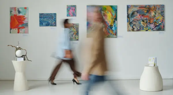 W galerii sztuki, gdzie obrazy zachęcają do kreatywności, jak w muzeum dla dzieci, dwie postacie w ruchu podziwiają abstrakcyjne dzieła.