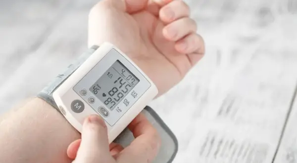 Dłoń z założonym ciśnieniomierzem nadgarstkowym pokazującym wynik 145/87 mmHg i puls 46/min.