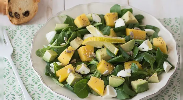 Deliciosa ensalada de lechuga con cubos de queso amarillo, aguacate, huevo cocido y semillas.