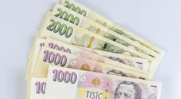 Kupka banknotów 1000 i 2000 koron czeskich, czyli waluta w Czechach, leży na białym tle.
