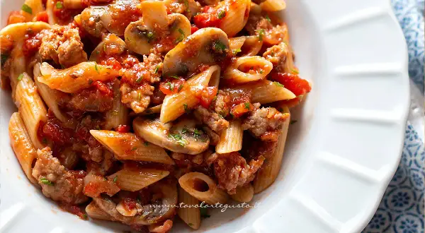 Piatto di pasta alla boscaiola con penne, funghi, salsiccia e pomodoro, un classico saporito.