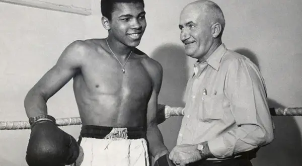 En ung Muhammad Ali ler mot sin tränare i ringen.