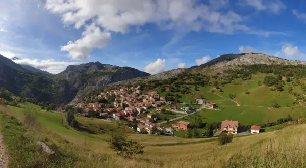 Pueblo de Sotres en los Picos de Europa, ideal para explorar sus rutas. Casas de piedra y tejados rojos entre verdes prados y montañas.
