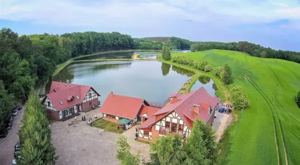 Malownicza osada rybacka Sazan z czerwonymi dachami, otoczona stawami i zielonymi polami.