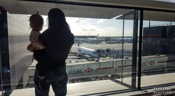 Mama z dzieckiem na rękach patrzy na samoloty. Czas na boarding, przygoda czeka!