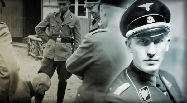 Ein junger Mann in Uniform der SS mit Totenkopf auf der Mütze. Im Hintergrund weitere Männer in SS-Uniformen.