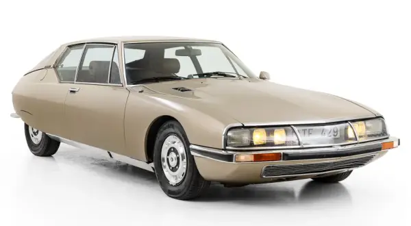 En beige Citroën SM, en av många ikoniska Citroën modeller, med sina distinkta linjer och strålkastare.