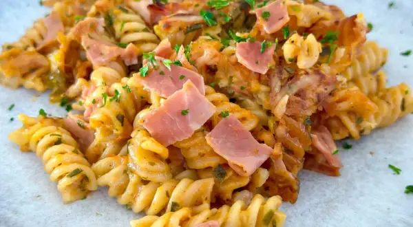Ein köstlicher Nudelauflauf mit Spiralnudeln, Schinken und Käse, garniert mit Petersilie.