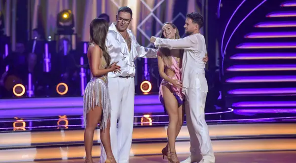 Cztery osoby w strojach tanecznych na scenie z fioletowym oświetleniem.