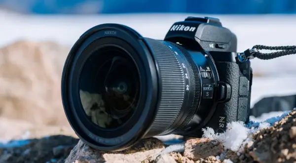 Nikon Z 50, jeden z popularnych bezlusterkowców, leży na kamieniach w zimowej scenerii.