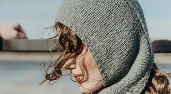 Una joven con un gorro tejido gris, que recuerda al balaclava origen, mira al horizonte.