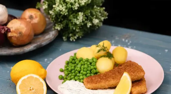 Panerad fisk med kokt potatis, gröna ärtor och en krämig sås som påminner om skolans kalla fisksås. Serveras med citron.