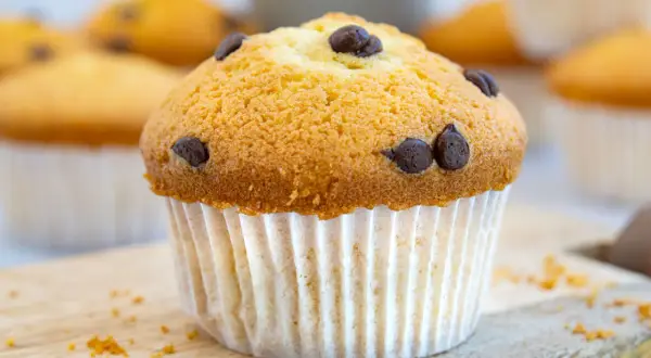 Ein goldbrauner Schoko-Muffin, perfekt für das Muffins Grundrezept. Mehrere Muffins im Hintergrund.