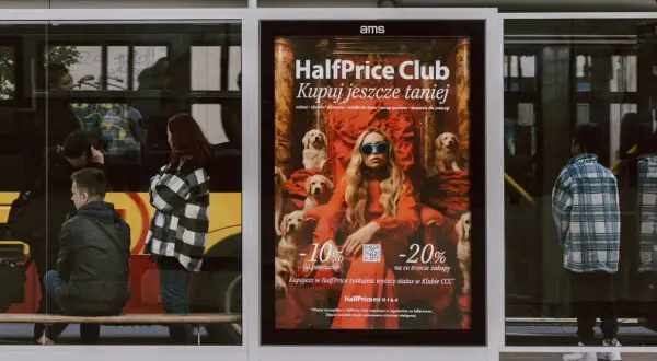 Plakat reklamuje HalfPrice Club, zachęcając do zakupów z rabatami. Aplikacja HalfPrice to szansa na niższe ceny.