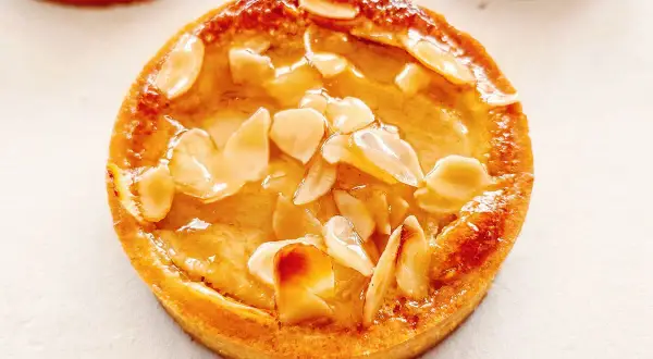 Tarte poire amandine dorée, garnie d'amandes effilées et d'un glaçage brillant. Un délice croustillant et fruité.