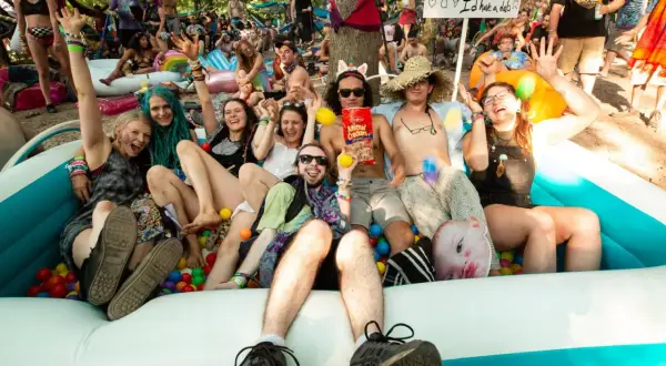 A group of friends enjoys a ball pit at the lil dub festival, laughing and posing for a photo.