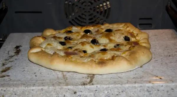 Pizza z oliwkami i serem, wypiekana na kamieniu biscotto w piekarniku.