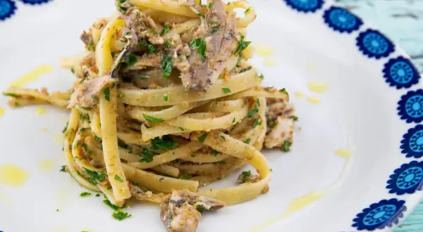 Un plat de pâtes linguine garni de sardines émiettées, de persil frais et de chapelure, un délice de pasta con le sarde.