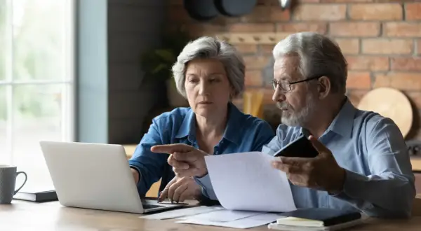 Para, mam 60 lat i 10 lat pracy, czy dostanę emeryturę? Zastanawiają się nad tym, analizując dokumenty i dane na laptopie.