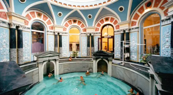 Wnętrze z basenem, gdzie ludzie relaksują się w gorącym źródle. Architektura z błękitnymi i pomarańczowymi zdobieniami.