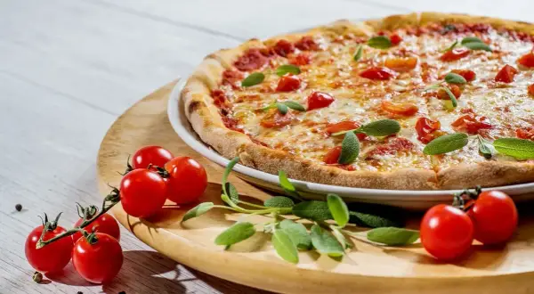 Pyszne ciasto na pizzę z jajkiem, pomidorkami i bazylią, gotowe do podania.