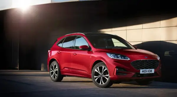 Czerwony Ford Kuga prezentuje swoje dynamiczne linie i imponujące ford kuga wymiary. Stylowy SUV na tle nowoczesnej architektury.