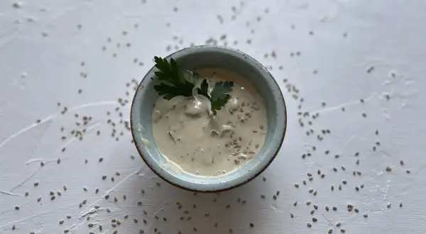 Cremige Sauce in einer Schale, garniert mit Petersilie und Sesam. Was ist Tahin? Eine köstliche Sesampaste, die hier als Dip serviert wird.