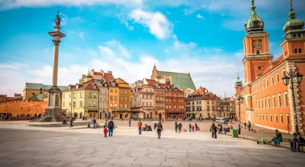 Kolumna Zygmunta i kolorowe kamienice na Rynku Starego Miasta. Warszawa atrakcje turystyczne w pełnym słońcu.