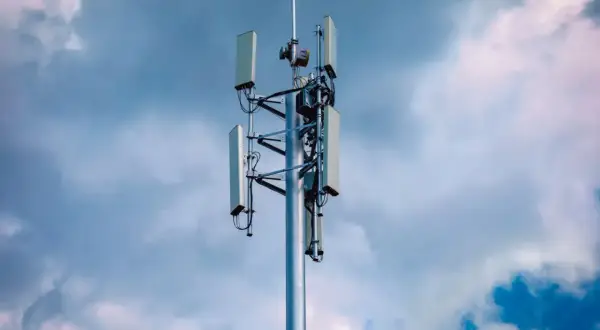 Wieża telekomunikacyjna z antenami, gotowa do obsługi sieci 5G, na tle burzowego nieba.