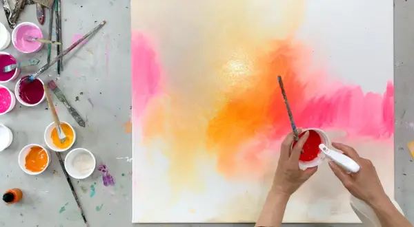 Bunte Farben auf einer Leinwand, bereit zum leinwand bemalen mit kindern. Pinsel und Becher mit Farbe liegen bereit.