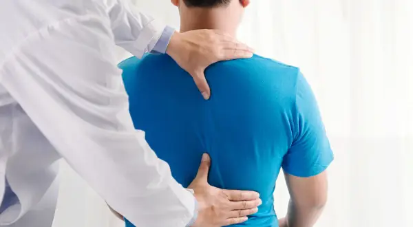 Un osteopata esamina la schiena di un paziente, aiutando a trovare sollievo dal mal di schiena.