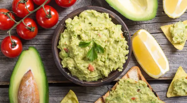 Miseczka guacamole, awokado, pomidorki i cytryna. Idealne składniki, by dowiedzieć się, co zrobić z guacamole – na toście lub nachos!