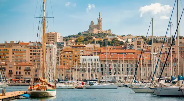 Segelboote im Hafen von Marseille, mit der Basilika Notre-Dame de la Garde im Hintergrund. Hier kann man viel unternehmen!