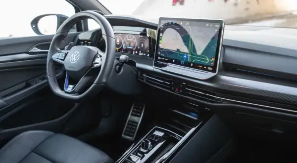 Wnętrze **Golf R 2025** z cyfrowymi zegarami i dużym ekranem nawigacji. Sportowa kierownica i eleganckie detale.
