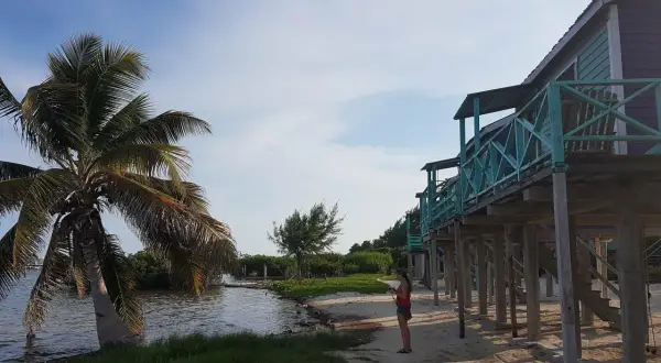 Kobieta na plaży, palmy i domki na palach. Idealne miejsce na belize wakacje.